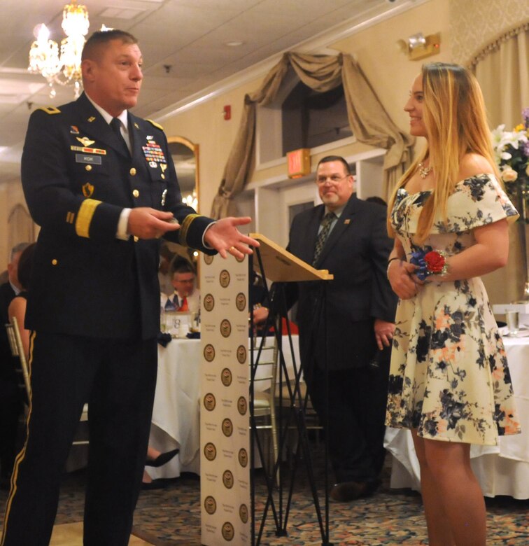Our Community Salutes, a not-for-profit organization, hosted it's yearly induction ceremony in Patchogue, N.Y. to honor high school seniors who have recently enlisted into the military.  Maj. Gen. Troy D. Kok, commanding general of the U.S. Army Reserve's 99th Regional Support Command, presents Samantha Braband, who has enlisted in the Navy, a challenge coin. In the background stands event organizer Bob Vecchio. Vecchio is chairman of Our Community Salutes Brookhaven Town Chapter and is also the president of the Board of Education for the William Floyd school district of Suffolk County, N.Y.