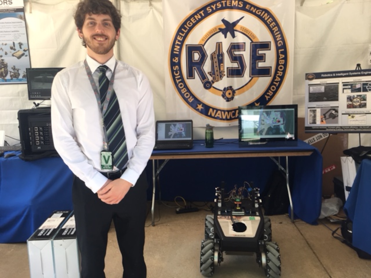A self-driving robot vehicle maneuvers itself next to Kyle Hart, a Naval Air Center Warcraft Division engineer attending DoD’s Lab Day at the Pentagon, May 18, 2017. NAWCAD designed the vehicle to navigate itself aboard an aircraft carrier. DoD photo by Rick Docksai