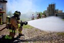 932nd Airlift Wing firefighters trained on core special skills particular to their jobs on May 21, 2017, at Scott Air Force Base, Illinois.   Airman Rachel Robert sprays water from the nozzle of he water hose connected to a fire truck  behind her, in preparation for her fellow firefighters to enter a smoke-filled building while searching for a simulated patient.  She ran this check on the system to ensure proper water pressure and availability of the resource in case it was needed to help put out a fire.   In the background, other 932nd Civil Engineering Squadron members suit up to take their turns and get the hot, dark, challenging experience. The 932nd Airlift Wing is part of 22nd Air Force, an Air Force Reserve Command unit located near Belleville, Illinois, and citizen airmen come to participate from 37 states.  (U.S. Air Force photo by Lt. Col. Stan Paregien)