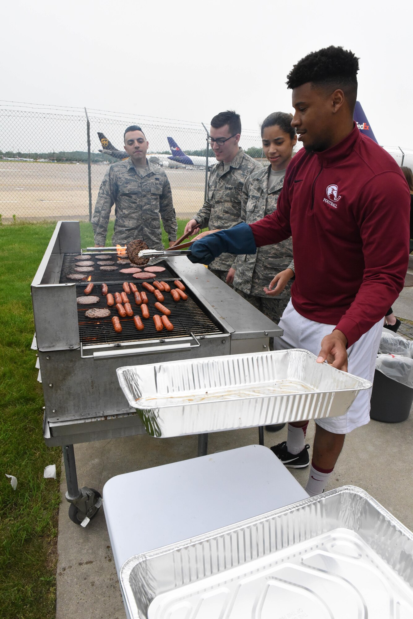 Volunteer Shaun Jones works the grill alongside 193rd Special Operations Wing, Middletown, Pa., services Airmen as part of the Burger Burn event hosted on base, May 20, by the Family Readiness office. Rachel Hoak, Airman and Family Readiness Program Manager, said more than 70 Airmen and family members attended the free event which included burgers, hot dogs, snacks and kids activities. (U.S. Air National Guard photo by Tech. Sgt. Claire Behney/Released)
