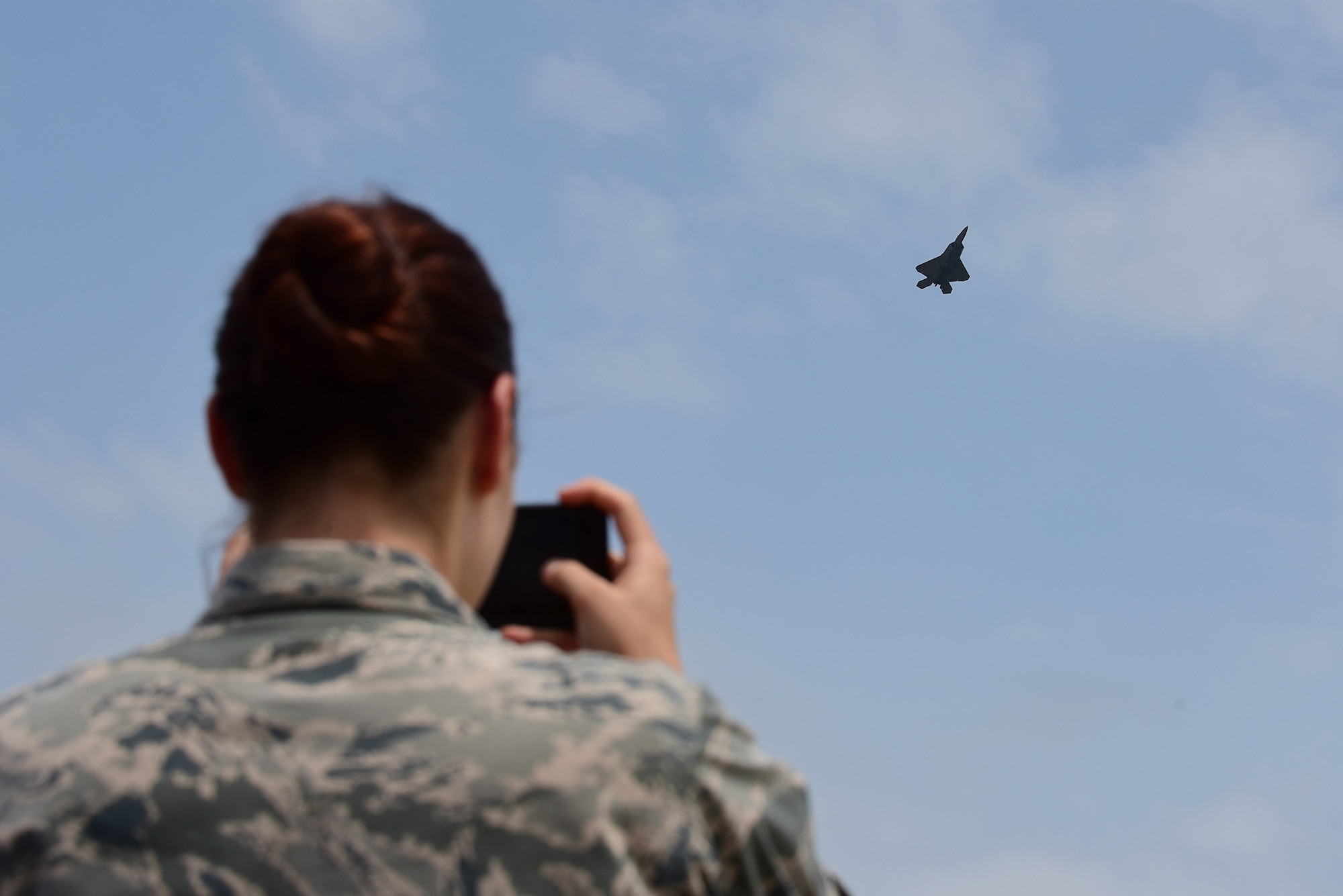 An Airman watches as Maj. Daniel Dickinson, F-22 Raptor Demonstration Team pilot, flies during the Wings Over Wayne Air Show, May 21, 2017, at Seymour Johnson Air Force Base, North Carolina. The fifth-generation fighter supports both air-to-air and air-to-ground missions vital to the 21st century Air Force. (U.S. Air Force photo by Airman 1st Class Kenneth Boyton)