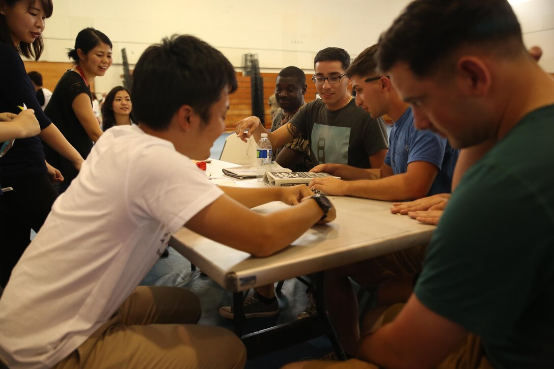 Marines with III Marine Expeditionary Force and Japanese students from Nikkei Business School in Okinawa City practice folding origami during the Okinawan-American Cultural Exchange Day, May 19, 2017, at House of Pain Fitness Center, on Camp Hansen, Okinawa, Japan. The Marines gave presentations about American culture and military operations to Japanese college students from Okinawa City and Naha, Okinawa. Marines with III MEF Headquarters Group hosted the cultural exchange day to strengthen bonds between the local community and service members, providing the two communities with the opportunity to converse and learn about each other’s culture. (U.S. Marine Corps photo by Sgt. Tiffany Edwards)