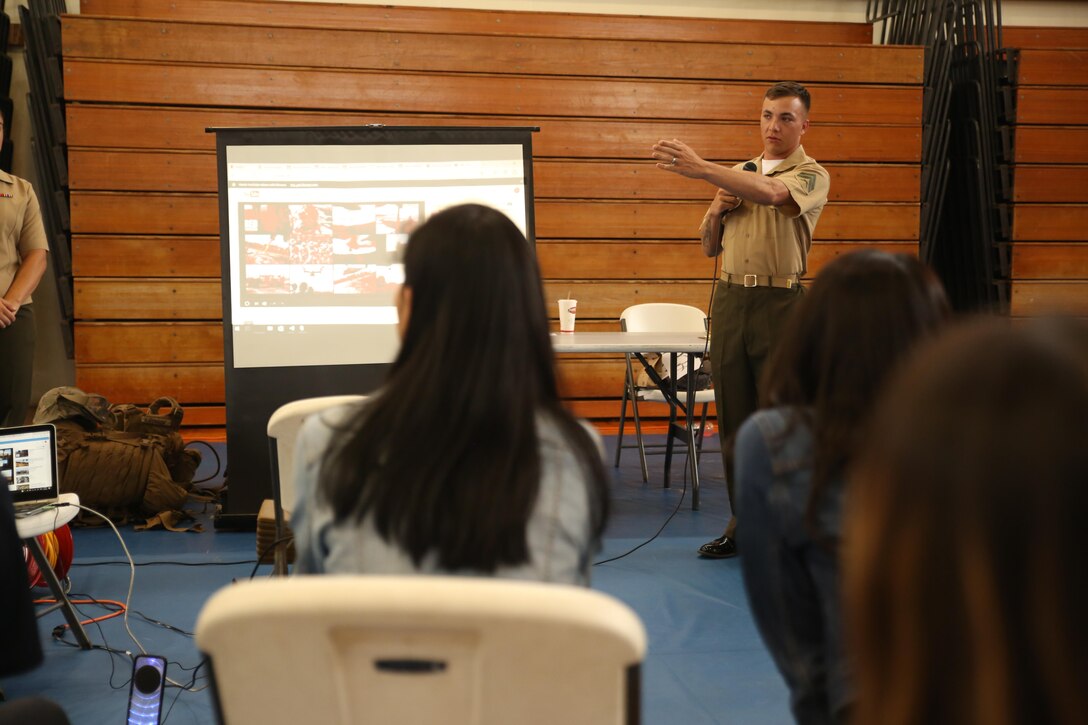 Cpl. Jared Colbridge, a squad leader with Landing Support Platoon, Combat Logistics Battalion 31, 31st Marine Expeditionary Unit, gives a presentation about helicopter external lift capabilities to Japanese students from Nikkei Business School in Okinawa City during the Okinawan-American Cultural Exchange Day, May 19, 2017, at House of Pain Fitness Center, on Camp Hansen, Okinawa, Japan. The Marines gave presentations about American culture and military operations to Japanese college students from Okinawa City and Naha, Okinawa. Marines with III MEF Headquarters Group hosted the cultural exchange day to strengthen bonds between the local community and service members, providing the two communities with the opportunity to converse and learn about each other’s culture. Colbridge, a native of Columbus, Ohio, is a landing support specialist with CLB-31, 31st MEU. (U.S. Marine Corps photo by Sgt. Tiffany Edwards)