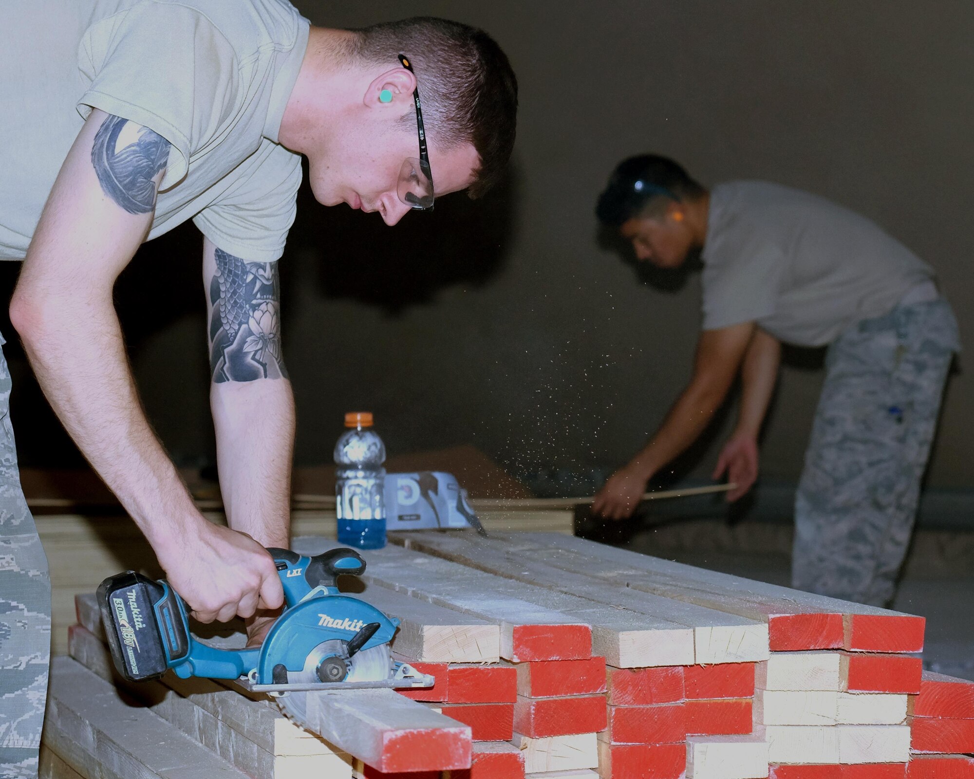 From left, Senior Airman Ryan and Airman 1st Class El John Julius, 380th Expeditionary Civil Engineer Squadron carpenters, cut lumber May 16, 2017, at an undisclosed location in Southwest Asia. Airmen used the lumber to create new offices for the 727th Expeditionary Air Control Squadron. (U.S. Air Force photo by Senior Airman Preston Webb)