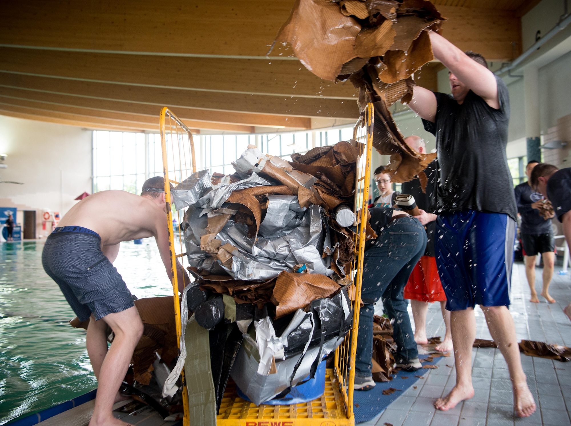 Airmen and 86th Force Support Squadron Ramstein Aquatic Center employees clean up the remains of cardboard battleships after the 2017 Battle of the Battleships on Ramstein Air Base, May 19, 2017. Teams competed in speed races and a "Last Ship Standing" event for medals and cash prizes during the community and morale event. (U.S. Air Force photo by Senior Airman Elizabeth Baker)