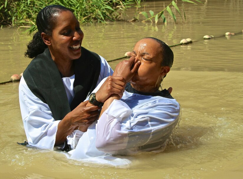 Maj. Pinkie Fischer, USARCENT operations chaplain, lowers Staff Sgt. Christal Crawford, USARCENT broadcast specialist, into the Jordan River as part of a baptism ceremony, May 5, 2017, in Jordan at the baptism site of Jesus.