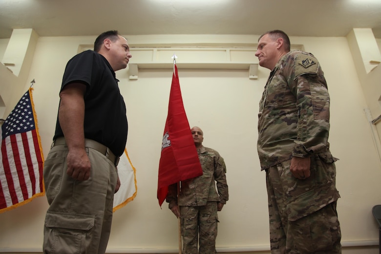 Col. Corey Spencer (right), commander of the U.S. Army Corps of Engineers – Transatlantic Division, Task Force Essayons, pauses after unfurling the unit guidon with Mr. Donny Davidson, Task Force Essayons deputy engineer for programs and project management (left), and Master Sgt. Eddie Rodriguez, Kuwait support cell non-commissioned officer-in-charge (center), during the Task Force Essayons activation ceremony, Friday, May 19, 2017 at Camp Taji, Iraq. (COMCAM Photo)