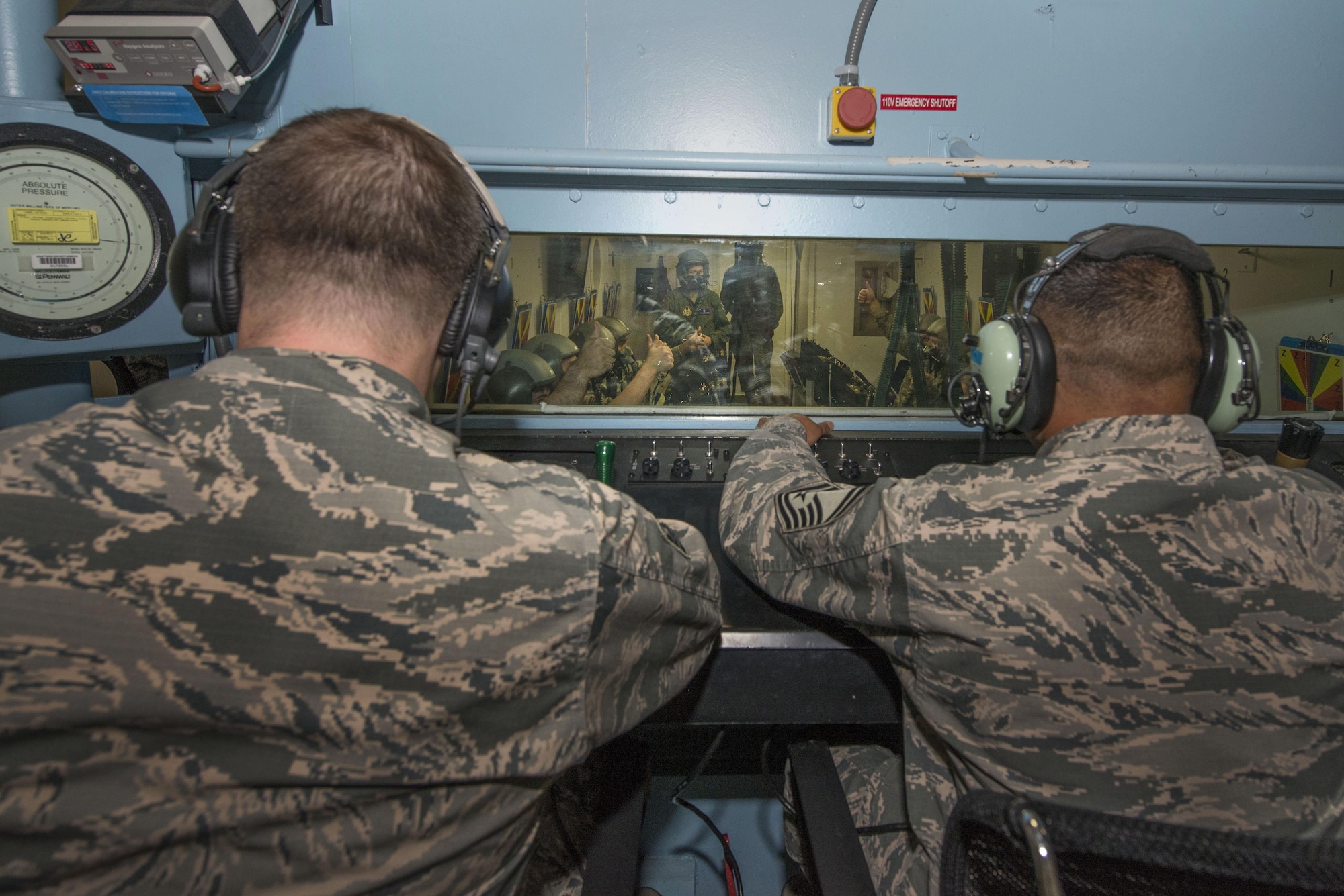 U.S. Air Force Tech. Sgt. Daniel Zerbe, (left) School of Aerospace Medicine operational physiology technician and Senior Master Sgt. Paul Johal (right), USAFSAM operational physiology superintendent, observe hypoxia demo training from the outside of the altitude hypobaric chamber during training at Wright-Patterson Air Force Base, Ohio, April 26, 2017. The hypobaric chamber provides a training system which replicates the effects of barometric pressure change on the human body. (U.S. Air Force photo/Michelle Gigante)