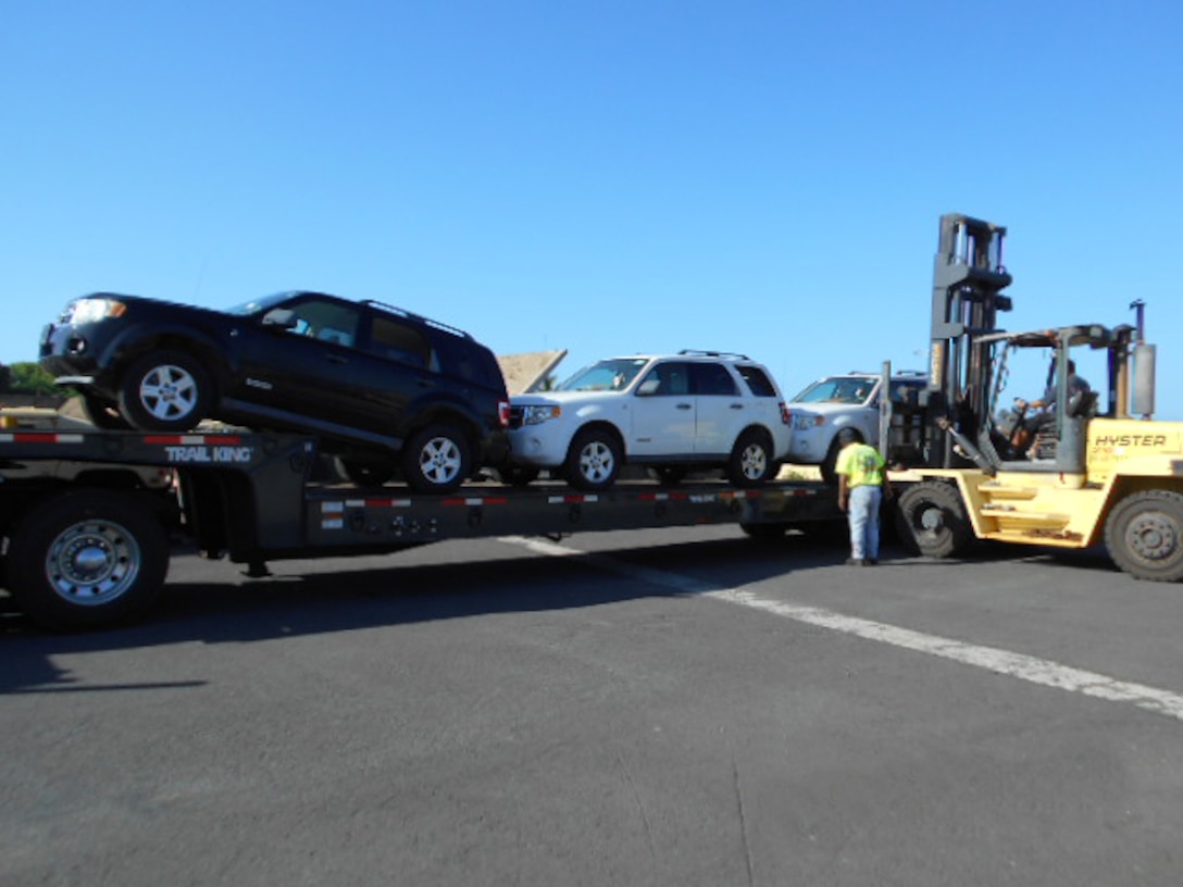 Workers load three 2008 Ford Escapes for their long journey from Hawaii to Moldova. 