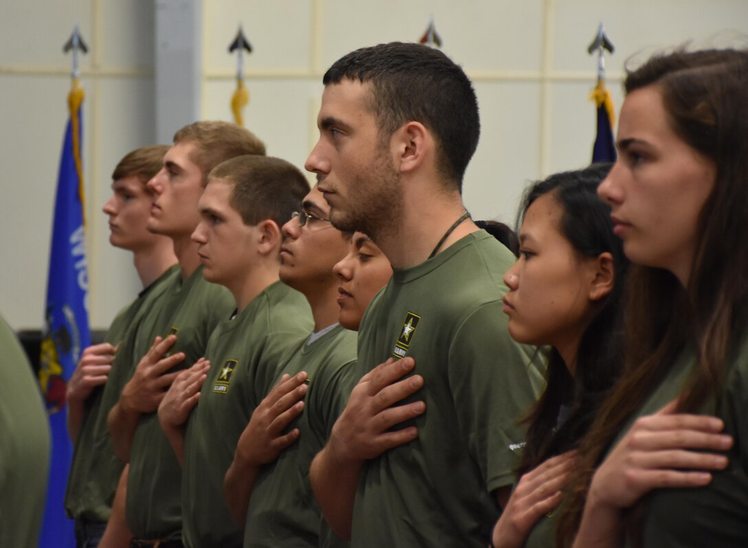 Graduating high school seniors who have committed to enlist in the Armed Forces following high school graduation stand as the National Anthem plays during an “Our Community Salutes” event at Fort McCoy, Wisconsin on Armed Forces Day, May 20, 2017.