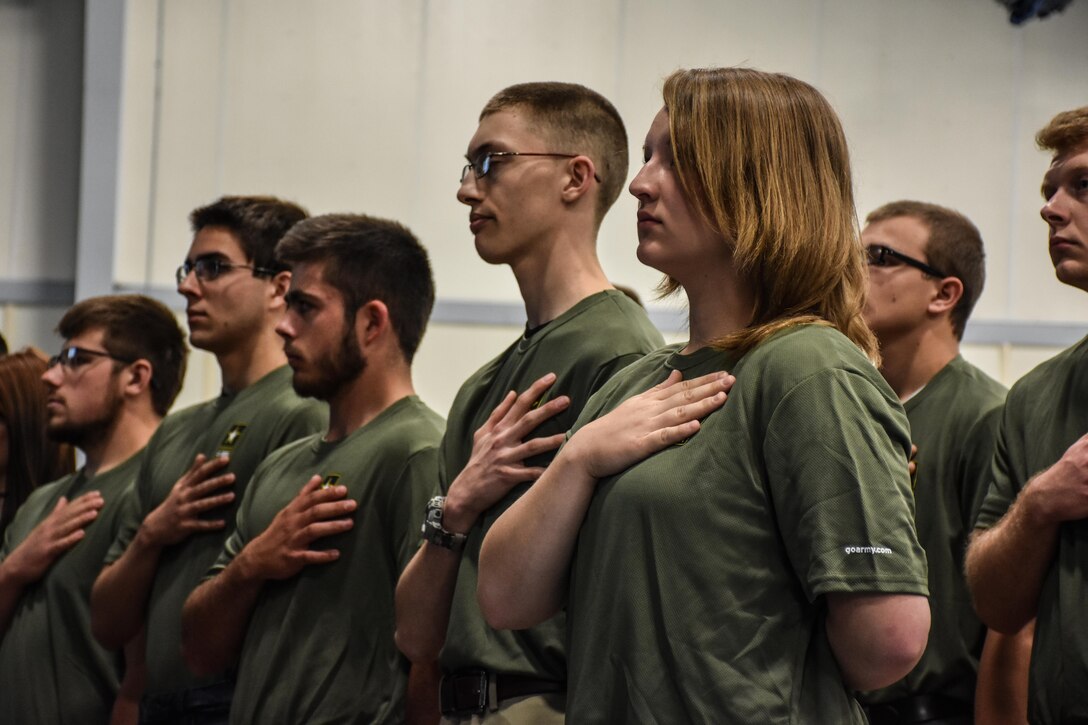 Graduating high school seniors who have committed to enlist in the Armed Forces following high school graduation stand as the National Anthem plays during an “Our Community Salutes” event at Fort McCoy, Wisconsin on Armed Forces Day, May 20, 2017.