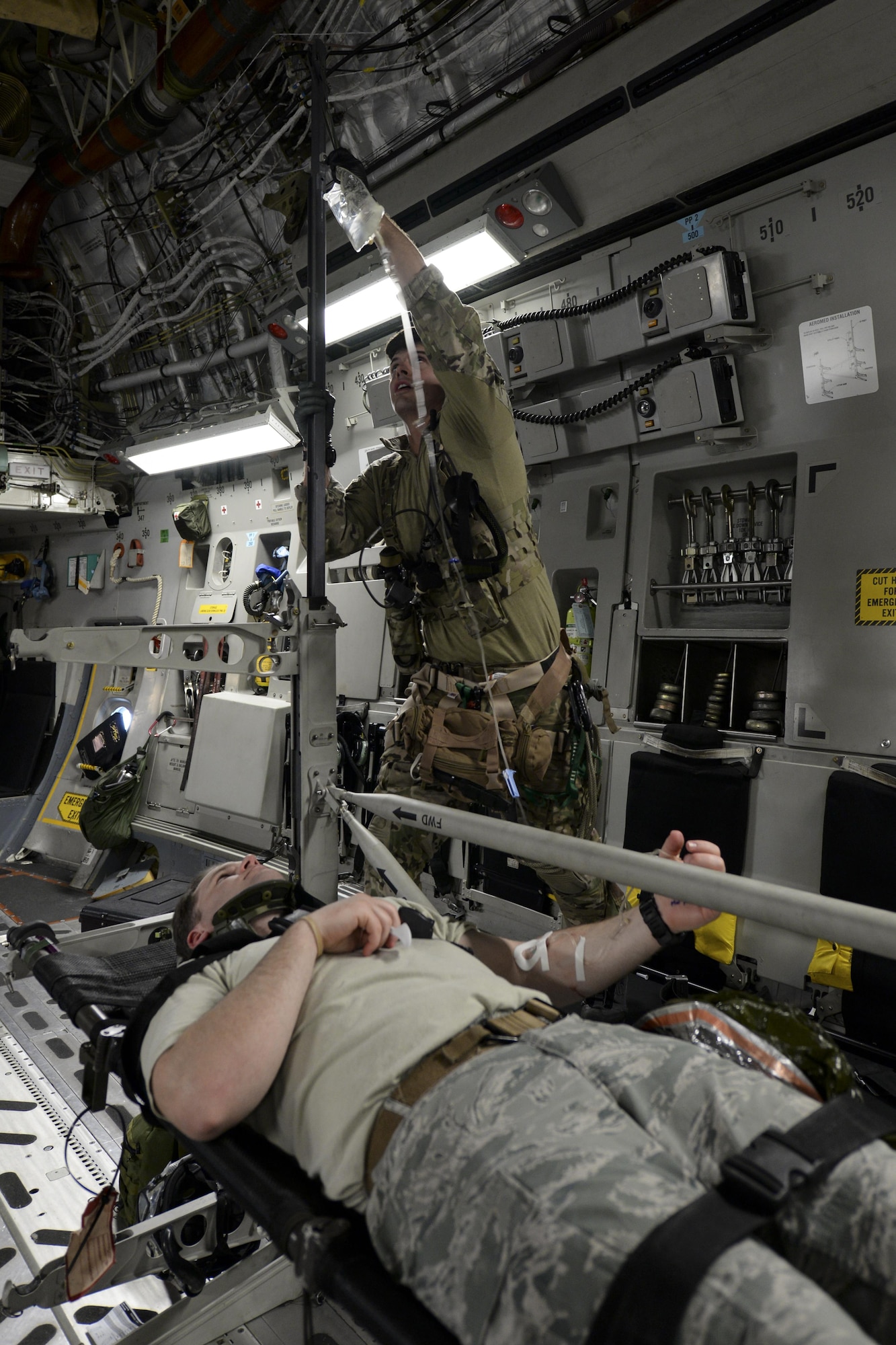 Senior Airman Jay Vinehout, 38th Rescue Squadron pararescueman assigned to Moody Air Force Base, Ga., hangs an IV bag for a simulated patient May 17, 2017, during Exercise RAPID RESCUE aboard a 3d Airlift Squadron C-17 Globemaster III. The plane flew around the coast of Va. for an hour while the 38th RS members practiced advanced medical techniques intended to stabilize patients with severe injuries. (U.S. Air Force photo by Senior Airman Aaron J. Jenne)