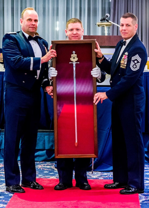 Brig. Gen. Keith M. Givens, the 17th Air Force Office of Special Investigations Commander, AFOSI Command Chief Master Sgt. Christopher VanBurger and Chief Master Sgt. Davy Davis pose with the personal sword presented to General Givens during his Order of the Sword Induction ceremony May 19, 2017, at Joint Base Anacostia-Bolling. The ceremonial sword is displayed at AFOSI Headquarters, Quantico, Va. (U.S. Air Force photo/Michael Hastings)  