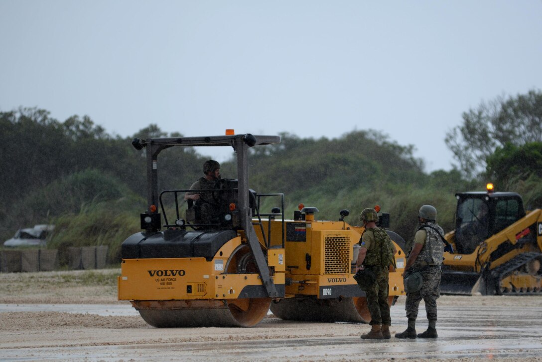 Royal Australian and U.S. Air Force members operate machinery in the rain during Silver Flag April 25, 2017, at Andersen Air Force Base, Guam. Silver Flag is a multilateral Theater Security Cooperation Program subject matter expert exchange event designed to build partnerships and promote interoperability through the exchange of civil engineer related information. 
