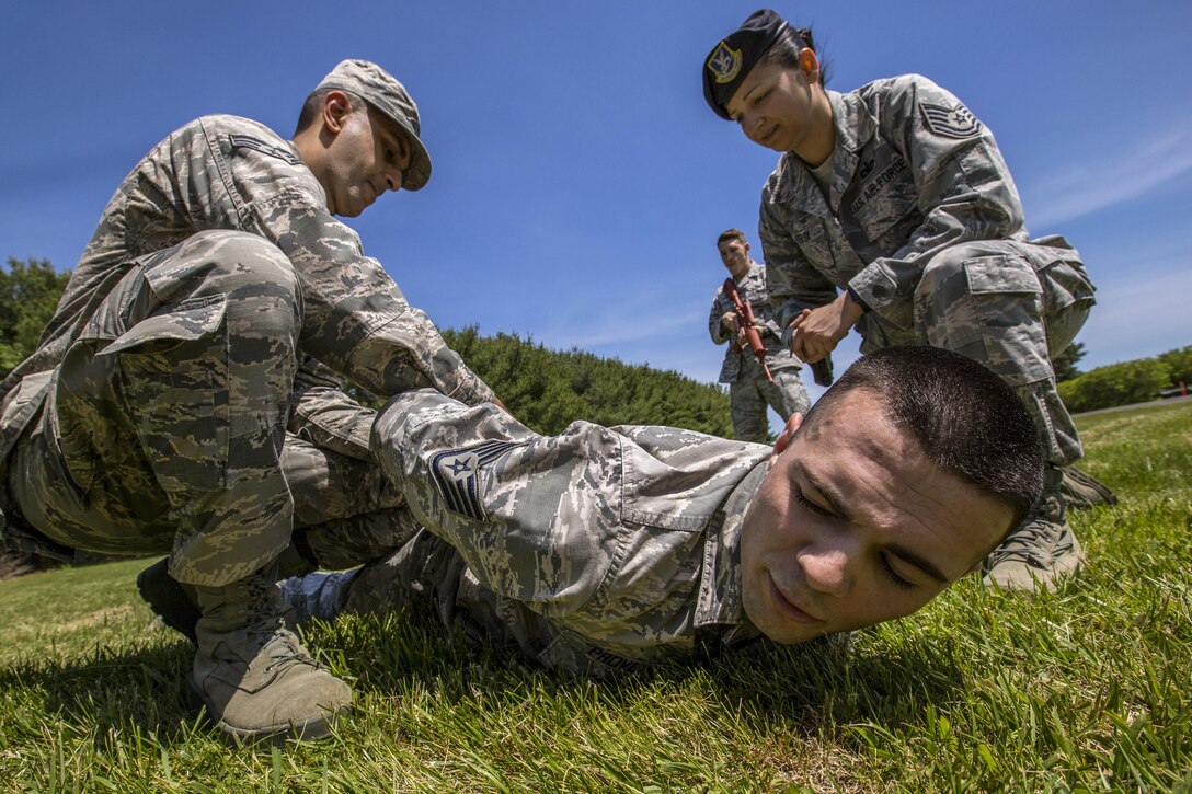 Air Force Tech. Sgt. Christina Felix, right, observes as Senior Airman Shantanu Rai handcuffs Staff Sgt. John Provence during static defense operations training at Joint Base McGuire-Dix-Lakehurst, N.J., May 21, 2017. Air Force photo by Master Sgt. Mark C. Olsen