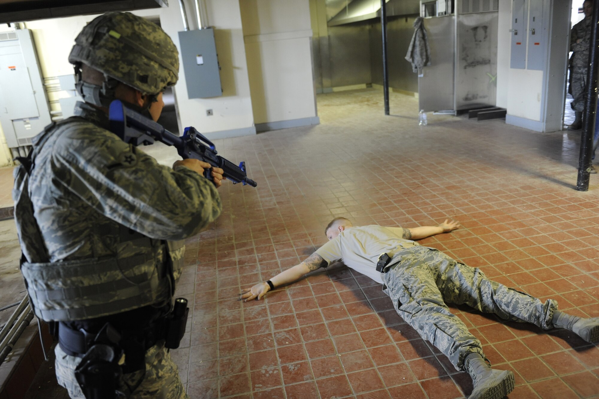 An Airman assigned to 99th Security Forces Squadron apprehends a simulated active-shooter during a training simulation in Area II on Nellis Air Force Base, Nev., May 17, 2017. The squadron is responsible for ensuring the safety of all base weapons, property and personnel from hostile forces. (U.S. Air Force photo by Senior Airman Kevin Tanenbaum/Released)