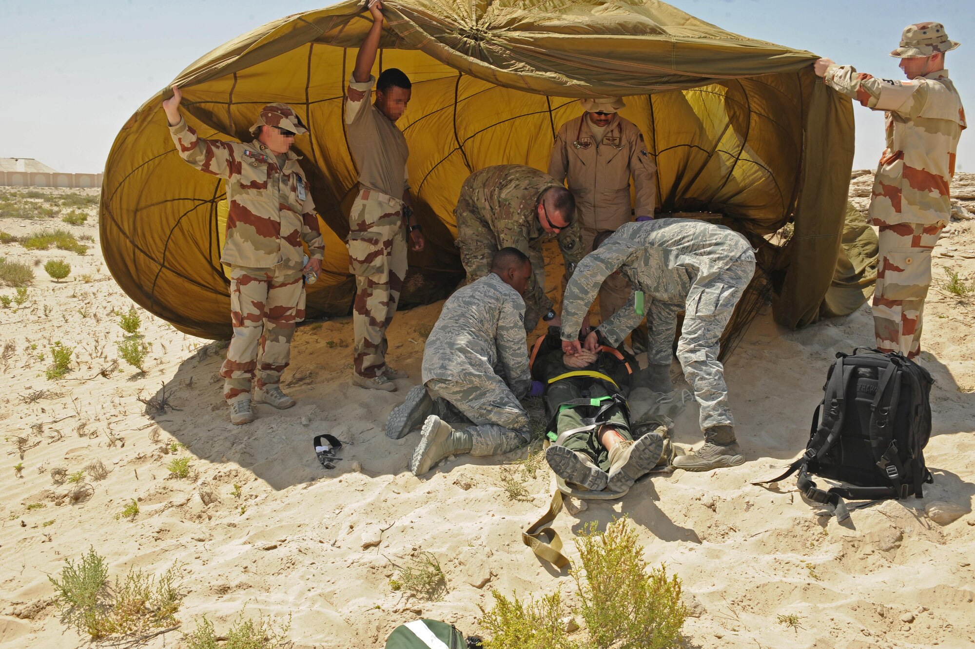 Members of the 380th Expeditionary Medical Group medical operations flight prepare a pilot for transport, with the assistance of French security forces, during a joint crash exercise at an undisclosed location in Southwest Asia, May 16, 2017. Coalition first responders worked together to provide joint response and care, and to simulate how they would respond in the event of an aircraft mishap. [Faces of French personnel have been obscured at the request of l'Armée de l'air.] (U.S. Air Force photo by Staff Sgt. Marjorie A. Bowlden)