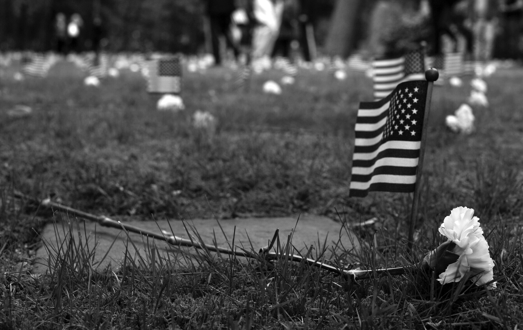 An American flag and flower adorns the gravestone of an American child during the Ramstein Area Chief's Group and German-American and International Women's Club's Kindergraves Memorial Service in Kaiserslautern, Germany, May 20, 2017. The Kindergraves are the final resting place for 452 American children who died at or shortly after birth from 1952 to 1971. Every year after Mother’s Day, members of the Kaiserslautern Military Community honor their memory with a memorial service. (U.S. Air Force photo by Senior Airman Tryphena Mayhugh)