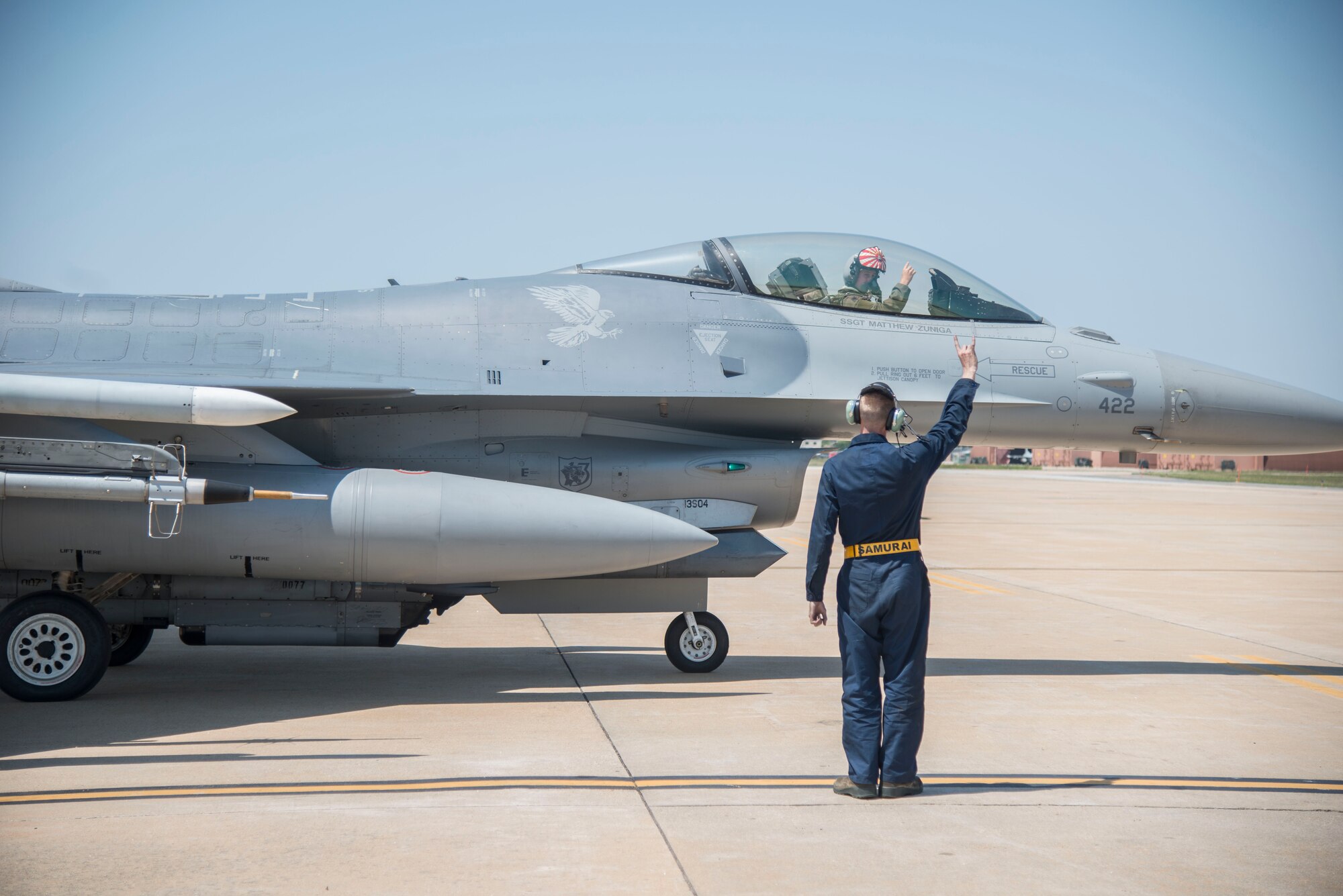 U.S. Air Force Airman 1st Class Evan Wilcox, a 35th Maintenance Group dedicated crew chief, holds up the 14th Fighter Squadron "wood" symbol while a pilot taxis at Kunsan Air Base, Republic of Korea, May 19, 2017. Wilcox had to trouble shoot an issue on the aircraft that required a pilot to test the system, ensuring it worked properly once repaired. (U.S. Air Force photo by Senior Airman Brittany A. Chase)