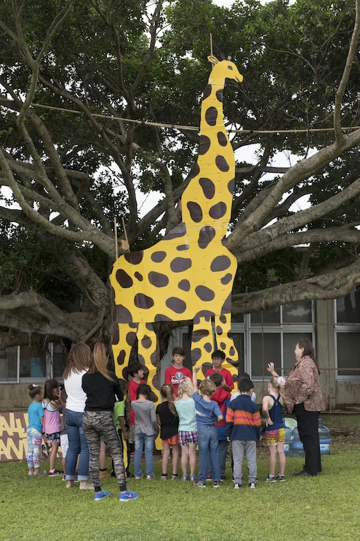 Children from Kadena Elementary School gather around a life-sized cardboard cutout of a giraffe May 22, 2017, during an interactive learning event at Kadena Air Base, Japan. The 20-foot tall giraffe was one of several life-sized models on display, to include the world's largest, longest and strongest animals. (U.S. Air Force photo by Senior Airman John Linzmeier)