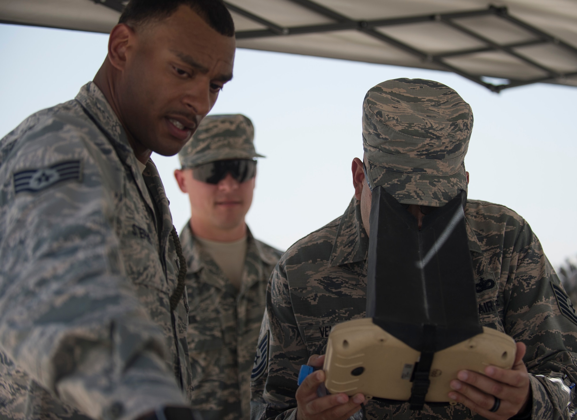 U.S. Air Force airman looks through a flight control module as Staff Sgt. Malcolm Stephen, left, assistant non-commissioned officer in charge of Raven B operations with 379th Expeditionary Security Forces Squadron, talks about what the RQ-11B Raven is showing on its color electro-optical camera at Al Udeid Air Base, Qatar, May 15, 2017. Airmen from the 379th ESFS organized a week of law enforcement activities to honor fallen civilian police officers, security forces airmen and U.S. Air Force Office of Special Investigations agents who died in the line of duty. (U.S. Air Force photo by Tech. Sgt. Amy M. Lovgren)