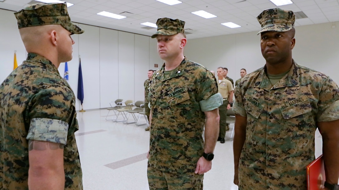 Cpl. David Qualls (left), a motor transport assistant operations chief with Marine Wing Support Squadron 471, 4th Marine Aircraft Wing, Marine Forces Reserve, Lt. Col. Vincent Dawson (center), the executive officer of Marine Aircraft Group 41, Marine Forces Reserve, and Sgt. Maj. Christopher Thomas, the Inspector-Instructor sergeant major at 1st Battalion, 23rd Marine Regiment, MARFORRES, stand at attention as Qualls’ Navy and Marine Corps Award citation is read at the 1/23 headquarters in Houston, Texas, May 20, 2017. In 2014, Qualls and other Marines helped save a man stuck inside a burning vehicle. According to the award summary, had he not arrived when he did, the man would have surely died. (U.S. Marine Corps photo by Cpl. Dallas Johnson)