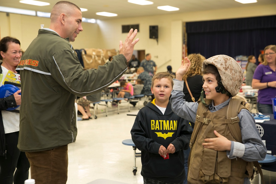 Staff Sgt. William Hobson, operations chief, G-1, U.S. Marine Corps Forces Command, high fives a student at Tarrallton Elemantary School in Norfolk, Va., after helping him put on tactical gear such as a Kevlar helmet, flak vest, and backpack, during a Military Child Appreciation event, April 24. The event was held to give the schools and communities in the city of Norfolk an opportunity to recognize the children of service members. (Official U.S. Marine Corps photo by Cpl. Logan Snyder/ Released)
