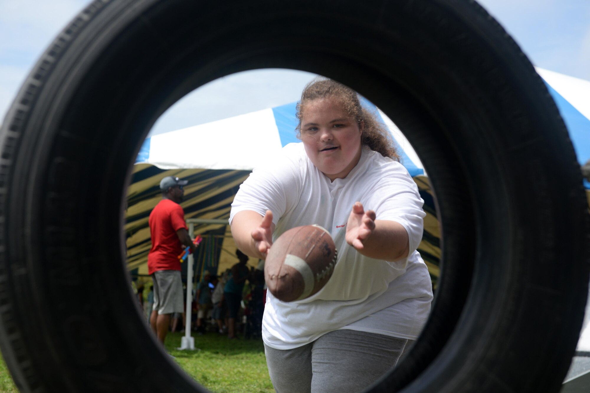 Madyson McManus, Area 3 athlete, throws a football through a tire during the Special Olympics Mississippi 2017 Summer Games at Olympic Village May 20, 2017, on Keesler Air Force Base, Miss. Keesler hosted more than 3,200 athletes, directors, coaches, family members and volunteers spanning over 16 regions across Mississippi for the 31st year. (U.S. Air Force photo by Airman 1st Class Travis Beihl)