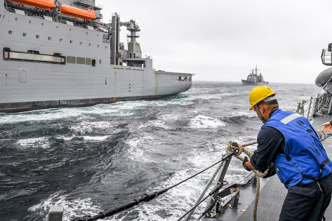 The Ticonderoga-class guided-missile cruiser USS Lake Champlain prepares to pull alongside Lewis and Clark-class dry cargo ship USNS Wally Schirra during a replenishment-at-sea, as Navy Petty Officer 3rd Class Ronaldjay Juego secures a lifeline aboard the Arleigh Burke-class guided-missile destroyer USS Wayne E. Meyer in the western Pacific Ocean, May 13, 2017. Juego is a boatswain’s mate. Navy photo by Petty Officer 3rd Class Kelsey L. Adams 