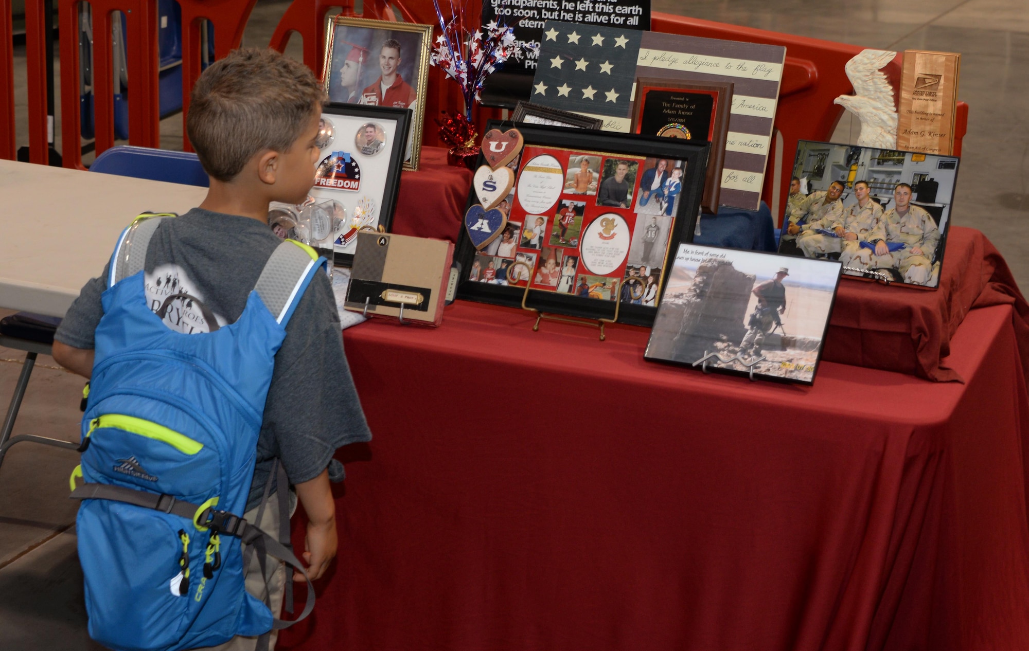 A child looks at a display in honor of Spc. Adam Kinser prior to the 7th Annual Gold Star Family's Ruck March at Travis Air Force Base, Calif., May 20, 2017. Kinser was a U.S. Army Soldier who was killed while on patrol in Afghanistan in 2004. The event featured 275 participants and is held every year by the Travis First Sergeant's Council to support Gold Star Families. (U.S. Air Force photo/Tech. Sgt. James Hodgman)
