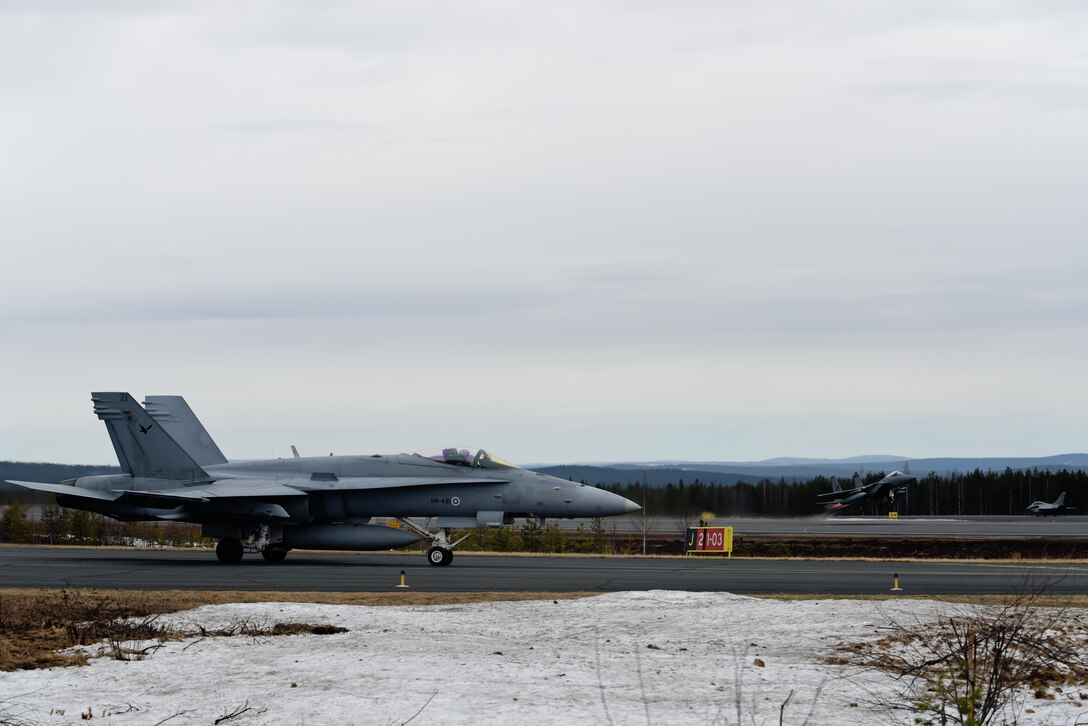 A Finnish F/A-18 Hornet waits while a U.S. Air Force F-15C Eagle takes off at Rovaniemi Air Base, Finland, May 22, in support of Arctic Challenge 2017. Finland is one of the hosts of the two-week long exercise, aimed at improving overall coordination between allies and partner militaries. (U.S. Air Force photo/Airman 1st Class Abby L. Finkel)