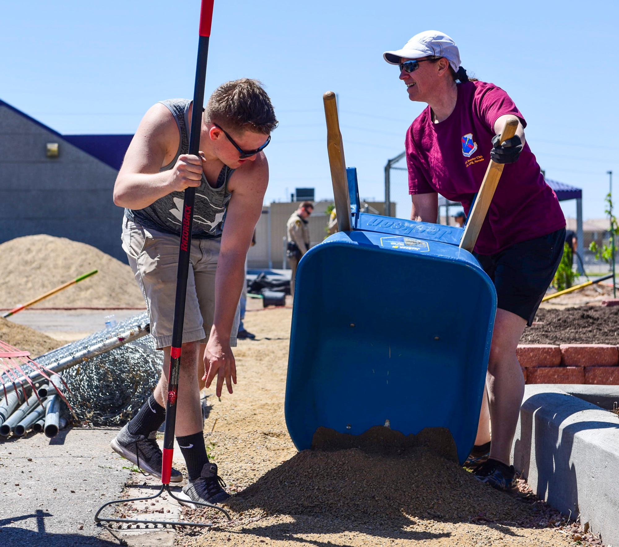 Col. Virginia Garner, 99th Medical Group commander, empties dirt from a wheelbarrow while Airman Logan Gaines, 99th Medical Group mental health technician, prepares to spread the dirt at a community garden between J.E. Manch and Zel & Mary elementary schools, May 12, 2017. Airmen from Nellis Air Force Base volunteered with community members to build a garden that will be used by the elementary schools for outdoor and environmental education. (U.S. Air Force photo by Airman 1st Class Andrew D. Sarver/Released)