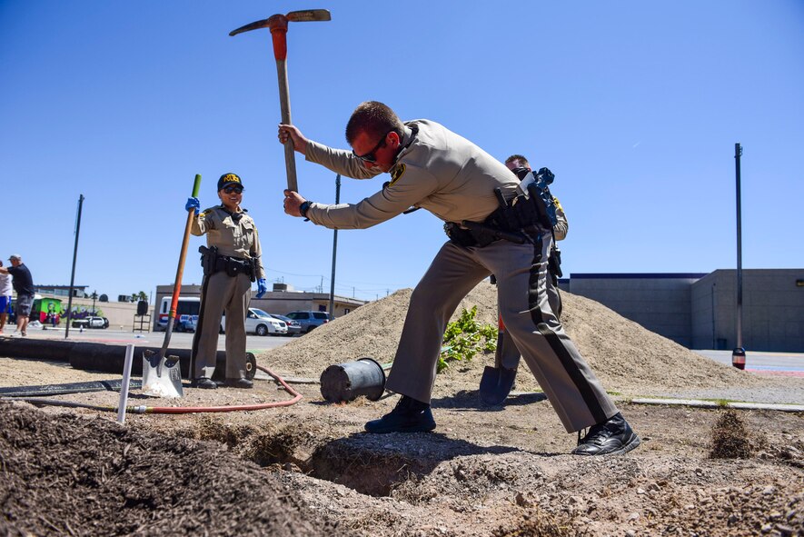 A Las Vegas Metro Police officer uses a pickaxe to loosen dirt at a community garden between J.E. Manch and Zel & Mary elementary schools, May 12, 2017. Members from the community, including Metro Police officers, local school teachers and Nellis Air Force Base Airmen, volunteered to plant trees, spread gravel and build benches and garden beds to create a garden for the elementary schools and neighborhood to use. (U.S. Air Force photo by Airman 1st Class Andrew D. Sarver/Released)