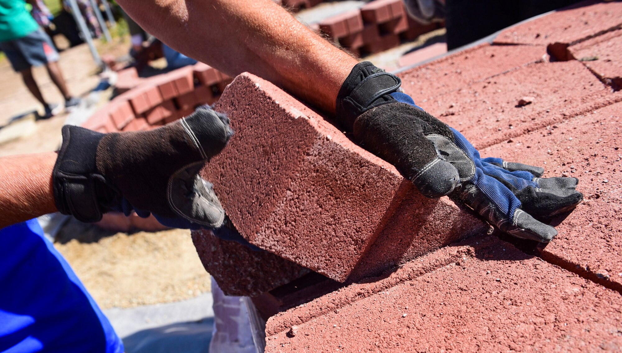 A volunteer removes a brick between J.E. Manch and Zel & Mary elementary schools, May 12, 2017. More than 150 community members gathered to build a neighborhood garden. The garden will serve as an outdoor classroom for students to learn about the importance of nutrition and growing fruits and vegetables. (U.S. Air Force photo by Airman 1st Class Andrew D. Sarver/Released)