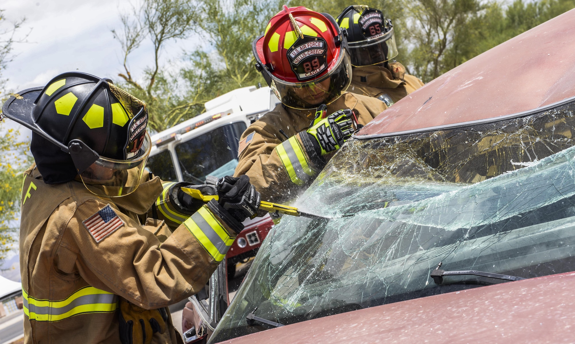 Firefighters from the 99th Civil Engineer Squadron remove a windshield during a simulated car crash at Nellis Air Force Base, Nev., May 17, 2017. The process of evacuating car crash victims includes removing the doors, cutting off the roof and raising the dashboard away from the front seats. (U.S. Air Force photo by Airman 1st Class Andrew D. Sarver/Released)