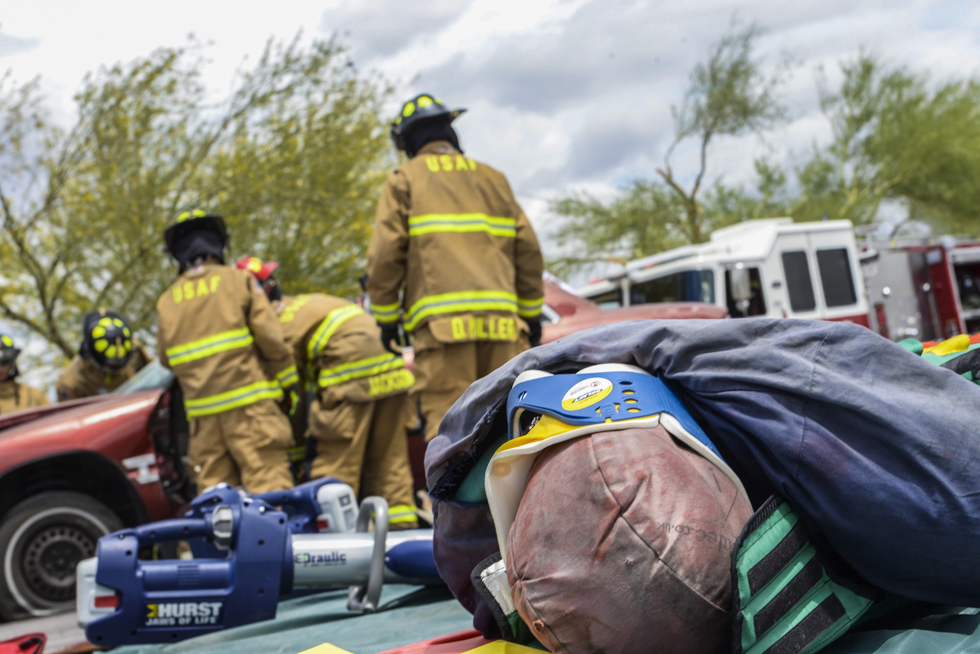 Firefighters from the 99th Civil Engineer Squadron prepare to lift the dashboard from the front seats of a simulated car crash at Nellis Air Force Base, Nev., May 17, 2017. The simulation required firefighters to respond to an overturned vehicle in which the victim had to be evacuated, by removing the doors and roof of the vehicle. (U.S. Air Force photo by Airman 1st Class Andrew D. Sarver/Released)