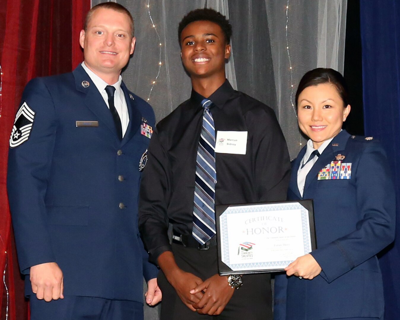 Air Force Lt. Col. Angie Blair and Chief Master Sgt. William Rawls pose with Vargas Sidney, a future Airman, who was honored during Our Community Salutes-San Antonio’s 6th Annual “A Night in Your Honor” held in the Rosenberg Sky Room at the University of the Incarnate Word.  Each honoree received an Our Community Salutes certificate and challenge coin from USAA.