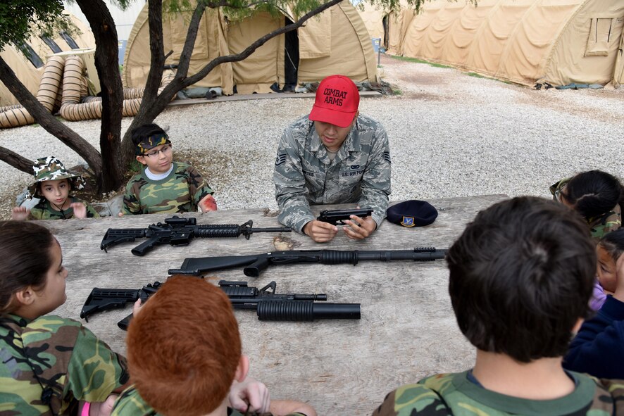 U.S. Air Force Staff Sgt. Nestor Reyes, 17th Security Force Squadron Combat Arms instructor, teaches children about Air Force issued weapons during Operation: Kids Investigating Deployed Services at Camp Sentinel on Goodfellow Air Force Base, Texas, May 20, 2017. The weapon familiarization and other activities gave the children a taste of a deployment. (U.S. Air Force photo by Staff Sgt. Joshua Edwards/Released)