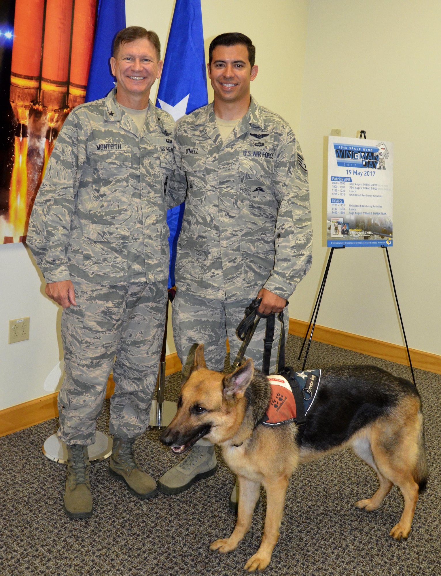 Brig. Gen. Wayne R. Monteith, (left), 45th Space Wing commander, Staff Sgt. August O’Niell, pararescueman and O'Niell's service dog Kai, pose after O'Niell gave a presentation on resiliency to 45th Space Wing Airmen May 19 as part of Wingman Day. O'Niell embarked on a 2011 deployment to save lives when he was shot through both legs during a combat rescue mission in Afghanistan. (U.S. Air Force photo SrA Brandon Kalloo Sanes)