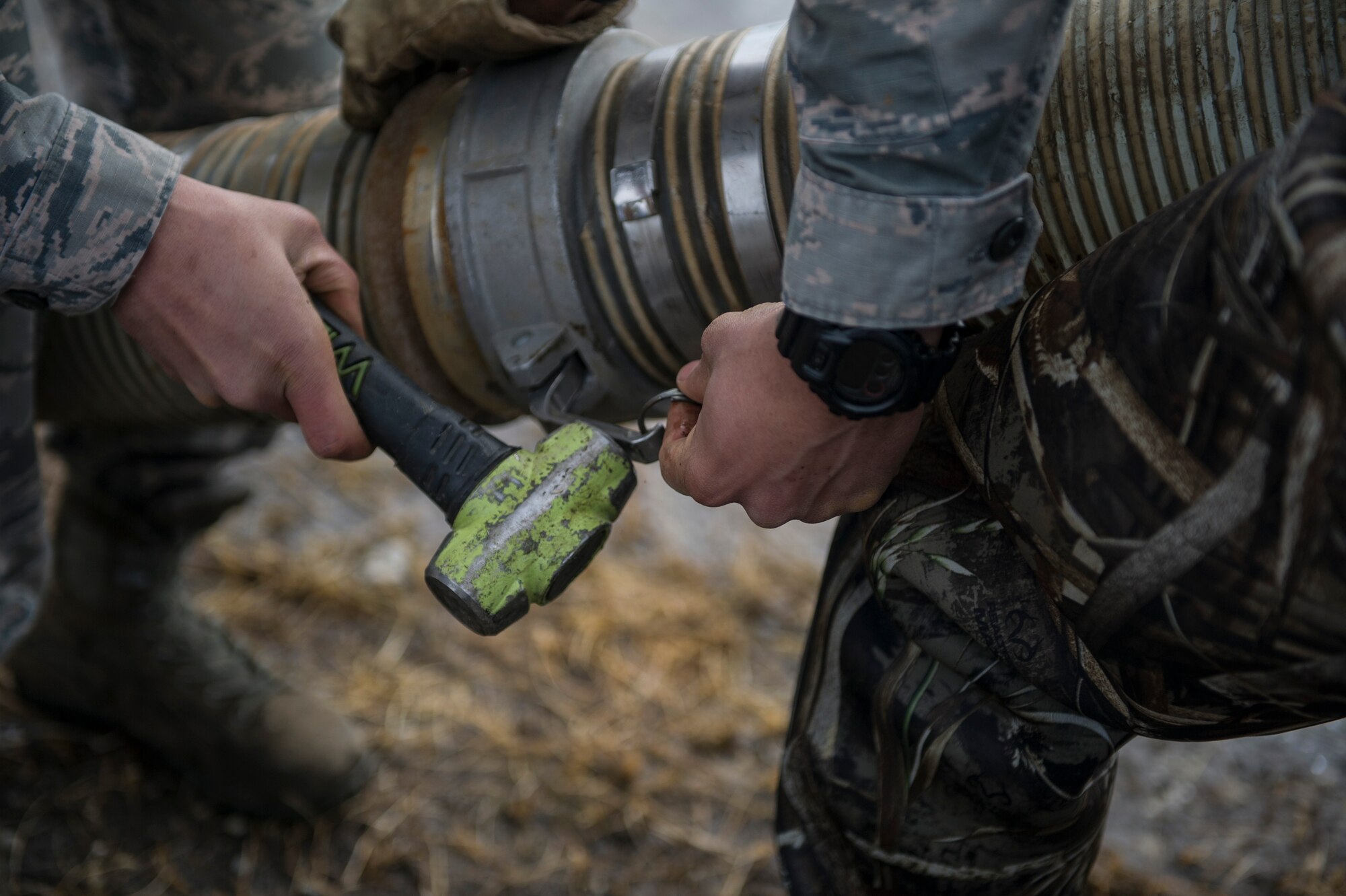 U.S. Air Force 354th Civil Engineer Squadron pavement and construction equipment operator Airmen, also known as “dirt boyz”, connect two hoses April 10, 2017, at Eielson Air Force Base, Alaska. “Dirt boyz” are responsible for making sure the flight line is always in a useable condition. (U.S. Air Force photo by Airman 1st Class Isaac Johnson)