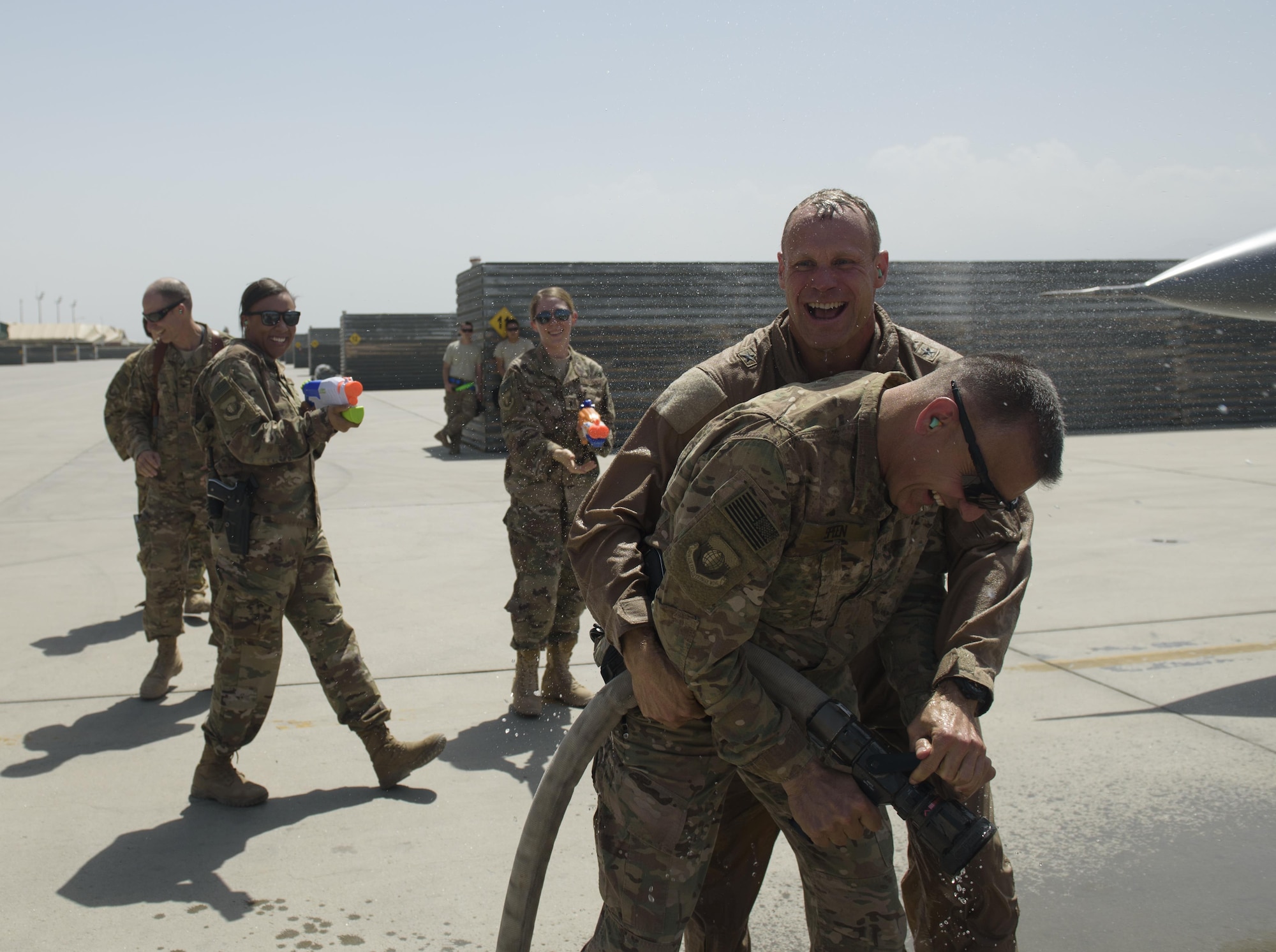 Brig. Gen. Jim Sears, commander of the 455th Air Expeditionary Wing, wrestles a fire hose away from Chief Master Sgt. Peter Speen, command chief of the 455th AEW, after completing his fini flight at Bagram Airfield, Afghanistan, May 22, 2017. Sears, who commanded the 455th AEW for the last 12 months, is a command pilot with more than 3,200 flying hours, including combat missions over Iraq and Afghanistan. (U.S. Air Force photo by Staff Sgt. Benjamin Gonsier)
