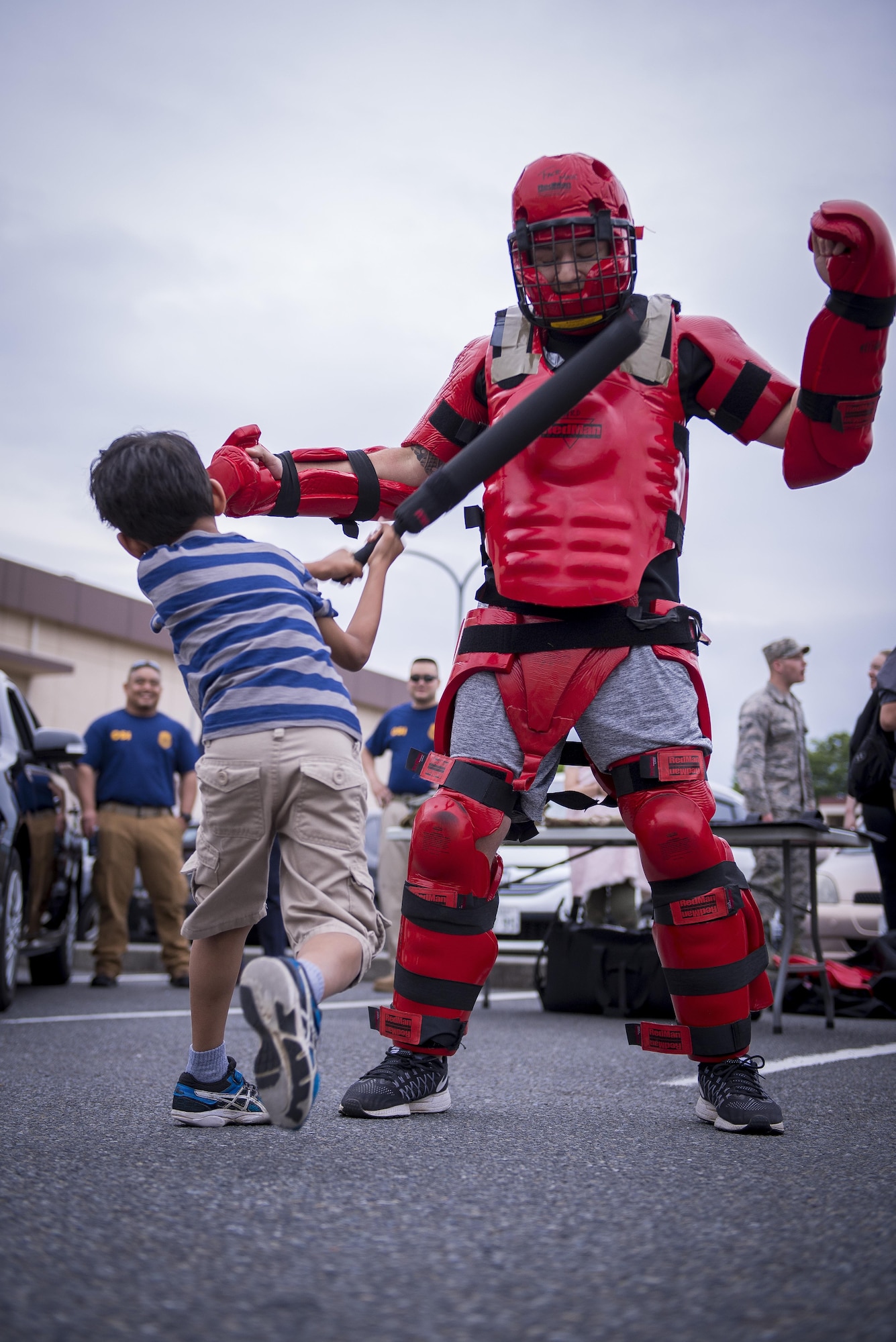 A child hits a 374th Security Forces Squadron member in padded training suit during a Police Week event, May 17, 2017, at Yokota Air Base, Japan. The event included displays and demonstrations of various vehicles, weapons and tools used by U.S. and Japanese law enforcement. (U.S. Air Force photo by Airman 1st Class Donald Hudson)