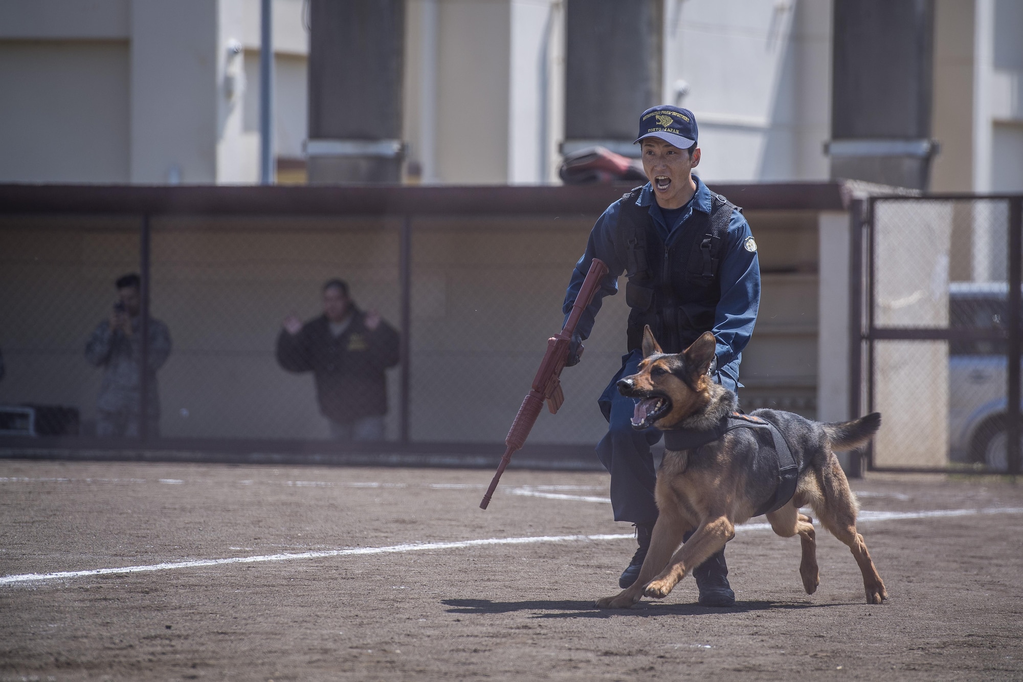 A Tokyo Metropolitan Police Department K-9 unit advance on a decoy suspect during a Police Week K-9 Unit tactical obstacle course competition, May 19, 2017, at Yokota Air Base, Japan. The competition included members of the Tokyo Metropolitan Police Department, 374th Security Forces Squadron and U.S. Army competitors. (U.S. Air Force photo by Airman 1st Class Donald Hudson)
