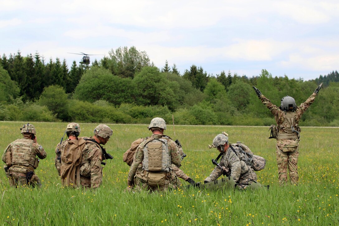 An Army crew chief signals an approaching UH-60 Black Hawk helicopter while soldiers prepare to load a mock casualty during training in Grafenwoehr, Germany, May 22, 2017. Army photo by Staff Sgt. Kathleen V. Polanco