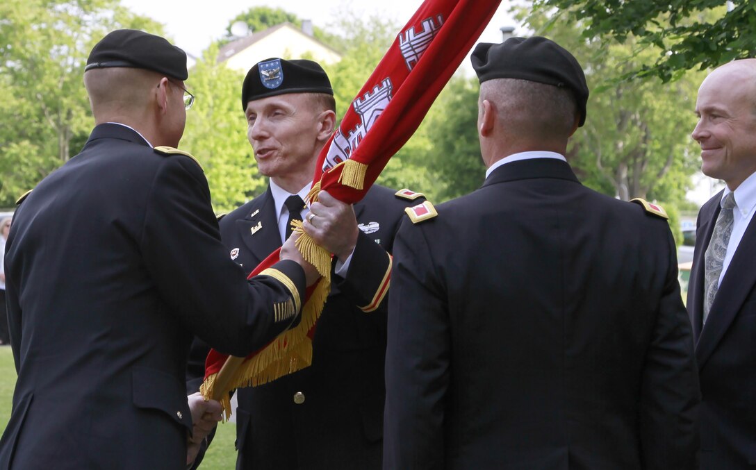 Col. John Baker, commander of Europe District, U.S. Army Corps of Engineers, accepts the guidon from Brig. Gen. William Graham, commander of the North Atlantic Division, U.S. Army Corps of Engineers, during the change of command ceremony May 24 at the Amelia Earhart Center in Wiesbaden, Germany. Deputy District Engineer John Adams, in the role of command sergeant major, passed the guidon to outgoing commander Col. Matthew Tyler and accepted the colors from Baker.