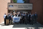 DAHLGREN, Va. - The Naval Laboratory Centers Coordinating Group (NLCCG) gathers outside of the Naval Surface Warfare Center Dahlgren Division (NSWCDD) headquarters as several members hold a poster depicting the Naval Research and Development Establishment commands and organizations.