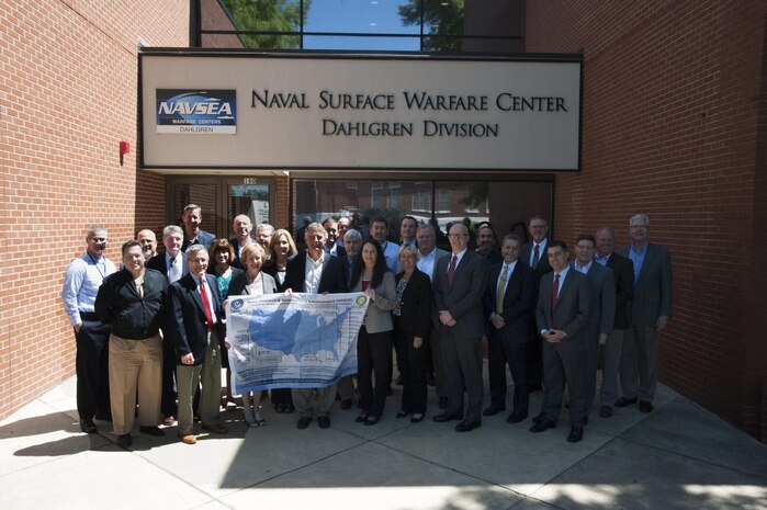 DAHLGREN, Va. - The Naval Laboratory Centers Coordinating Group (NLCCG) gathers outside of the Naval Surface Warfare Center Dahlgren Division (NSWCDD) headquarters as several members hold a poster depicting the Naval Research and Development Establishment commands and organizations.