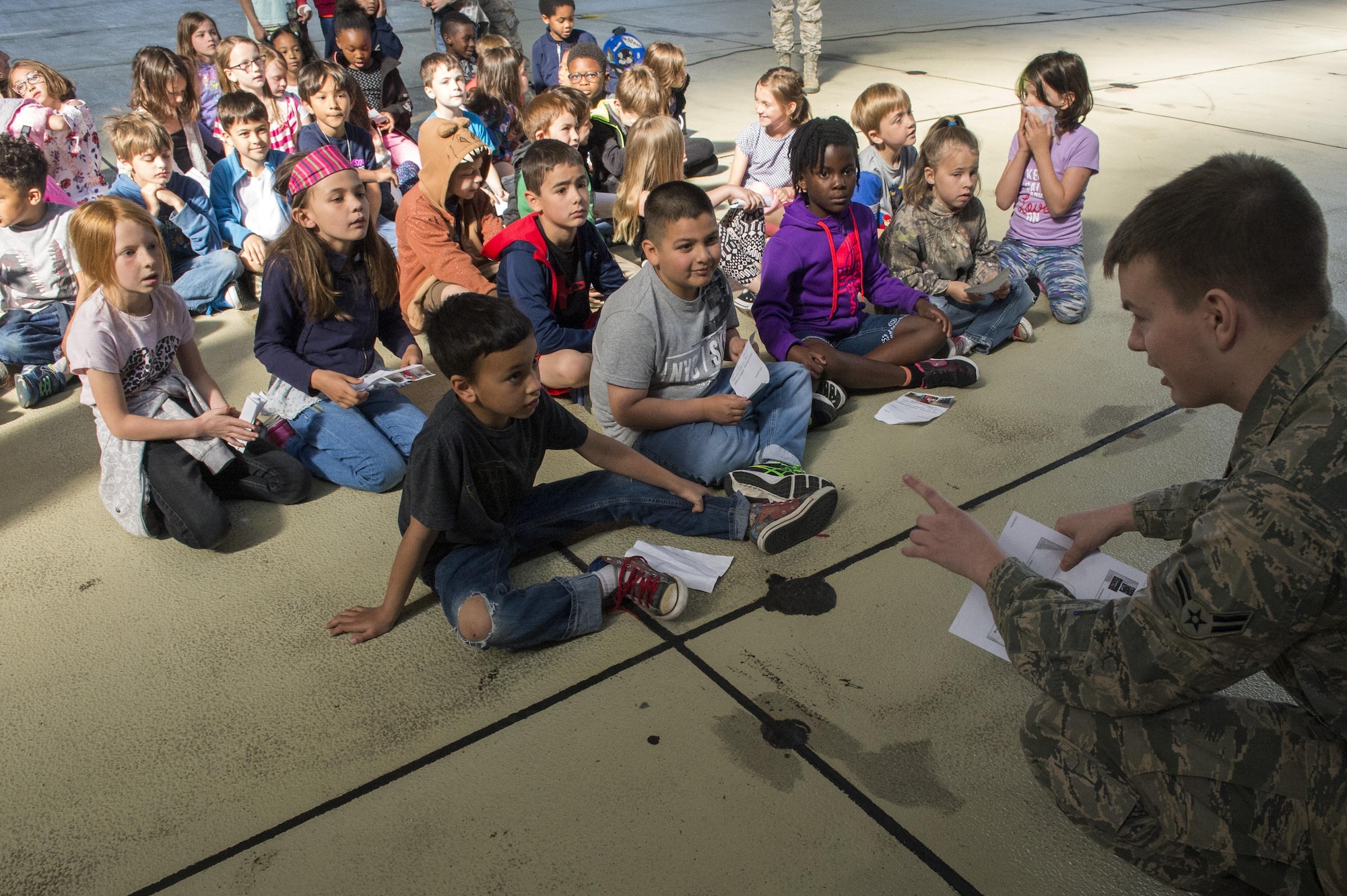U.S. Air Force Airman 1st Class Kyle Hamby, 52nd Operations Support Squadron intelligence analyst, speaks to Spangdahlem Elementary School students during Children’s Deployment Days at Spangdahlem Air Base, Germany, May 22, 2017. The event was a three-day simulated deployment line for students in kindergarten through fifth grade and consisted of a mock pre-deployment brief, a look at individual protective equipment, mock immunizations, static vehicle displays and a tour of a C-17 Globemaster III aircraft. (U.S. Air Force photo by Airman 1st Class Preston Cherry)