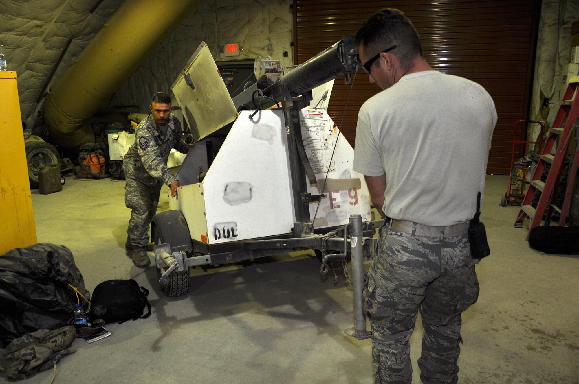 Staff Sgt. Jordan Lemay and Master Sgt. Daniel Romine, 386th Expeditionary Civil Engineer Squadron light cart team members, move a light cart into the maintenance bay at the 386 ECES Power Production facility.  The Power Pro light cart mission provides night-time illumination to many critical missions on base. (U.S. Air Force photo/Master Sgt. Eric Sharman)