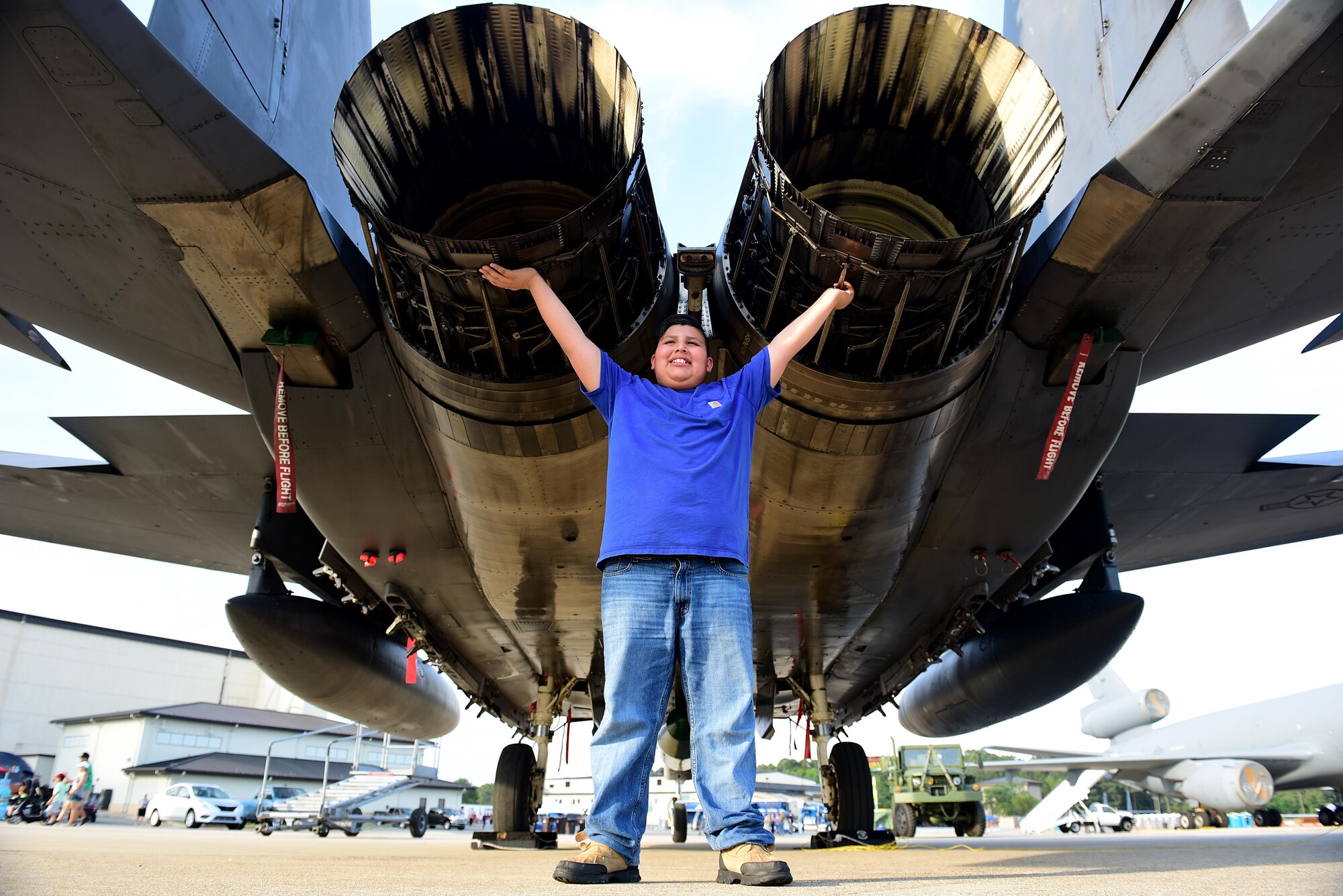 A young boy in attendance at the Wings Over Wayne air show stands beneath an F-15E Strike Eagle while posting for a photo, May 19, 2017. Airmen and their families attended a hangar party with free food and drinks the day prior to the air show at Seymour Johnson Air Force Base, N.C. The Navy’s premiere aerial demonstration team, the Blue Angels, headlined the air show. (U.S. Air Force photo/Airman 1st Class Kenneth Boyton)